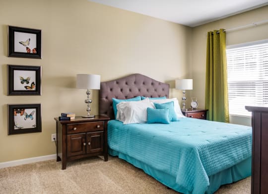 a bedroom with a bed and two nightstands and a window