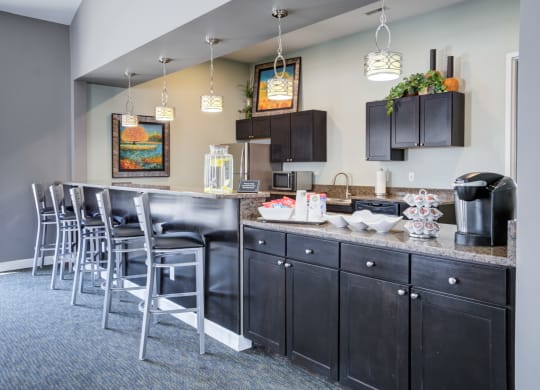 a kitchen with bar stools and a counter with chairs