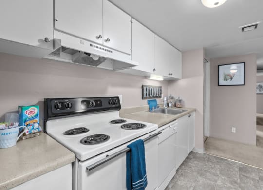 a kitchen with white appliances and white cabinets and a sink