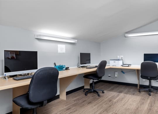 two computers and two chairs in an office