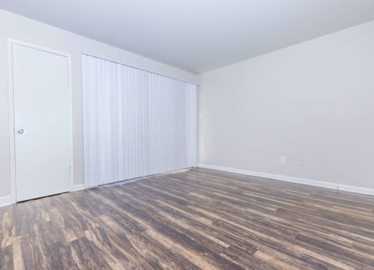 an empty room with wood flooring and white walls and doors
