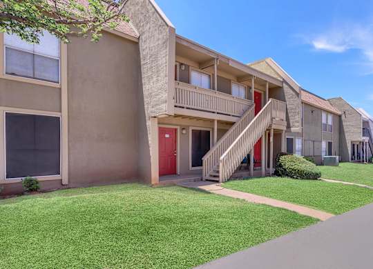 Apartment building with a red door and stairs leading to the entrance.