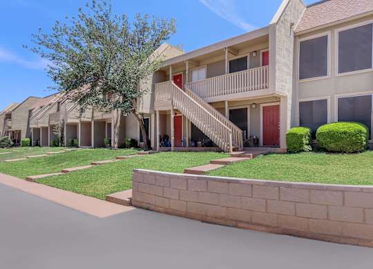 a street view of a row of apartments with grass and trees