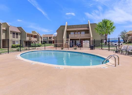 A swimming pool in a residential area with houses in the background.