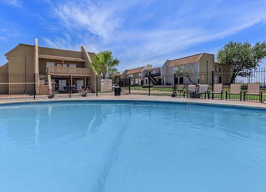 a swimming pool in front of a building with apartments in the background