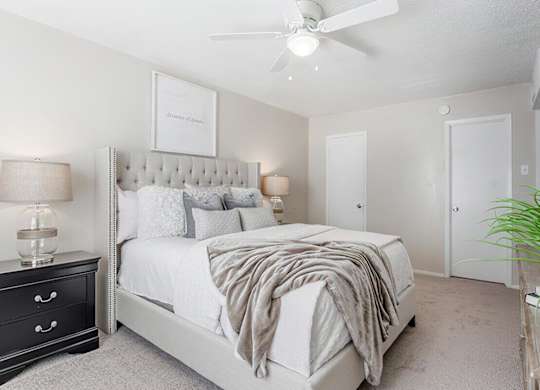 a white bedroom with a bed and a ceiling fan