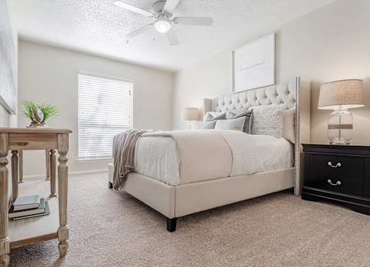 a white bedroom with a large bed and a night stand