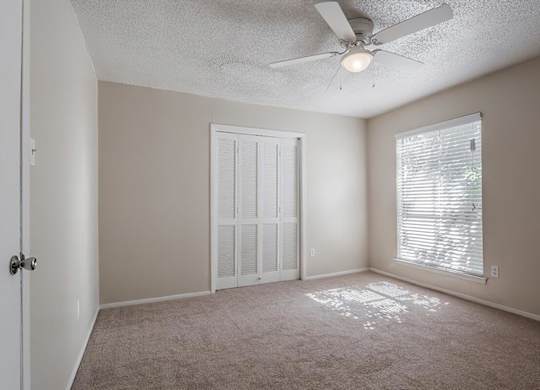 a bedroom with a ceiling fan and a window