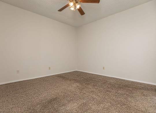 an empty room with carpet and a ceiling fan