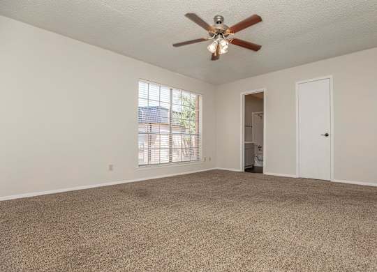 an empty living room with a ceiling fan and a window