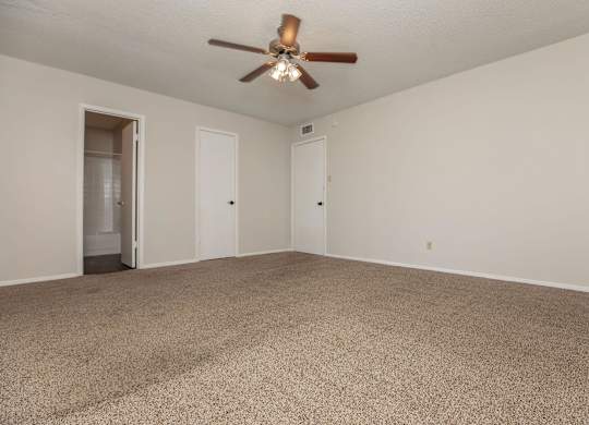 a spacious living room with carpet and a ceiling fan