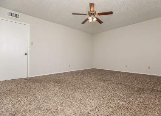 an empty living room with carpet and a ceiling fan