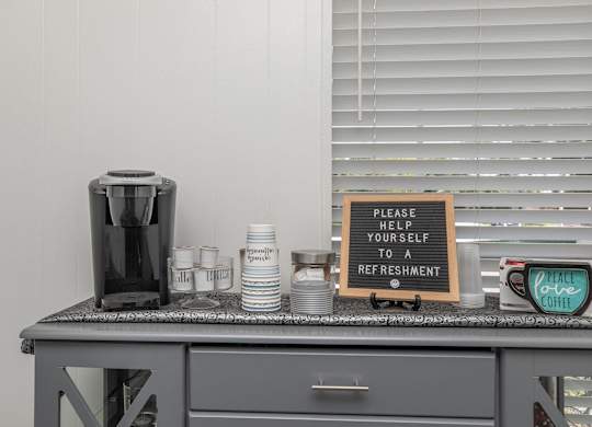a kitchen counter with a coffee maker and a sign that says praise your self to