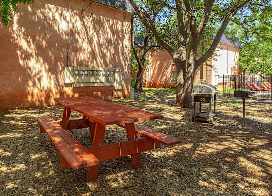 a picnic table in the yard of a building with a grill