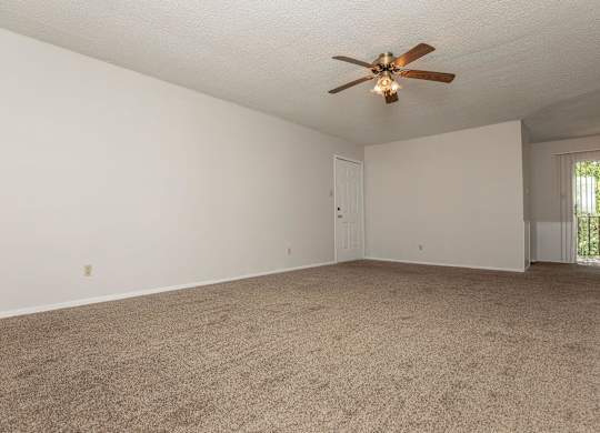 an empty living room with a ceiling fan