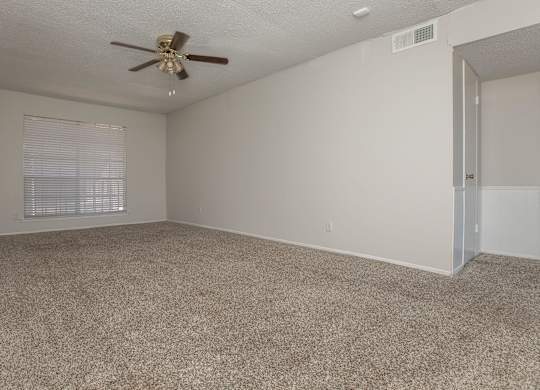 an empty living room with carpet and a ceiling fan
