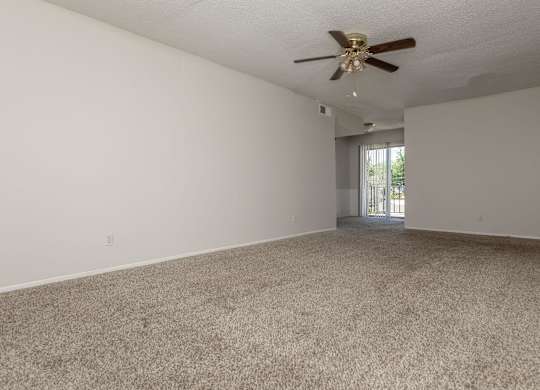 an empty living room with carpet and a ceiling fan