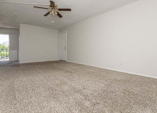 an empty living room with carpet and a ceiling fan