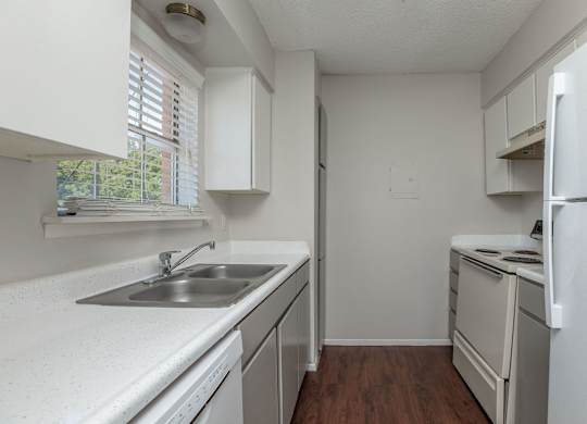 an empty kitchen with white appliances and white cabinets