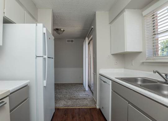 an empty kitchen with white cabinets and a white refrigerator