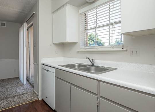 a kitchen with white cabinets and a sink and a window