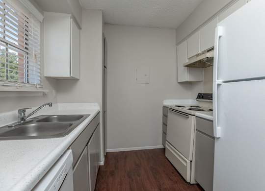 an empty kitchen with white appliances and white cabinets