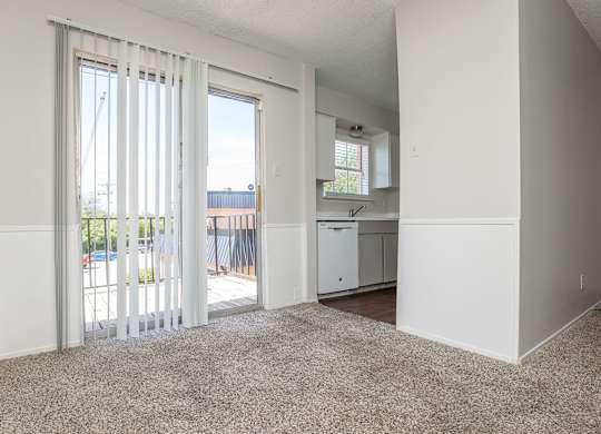an empty living room with sliding glass doors to a kitchen