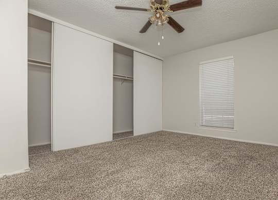 an empty living room with a ceiling fan and a closet