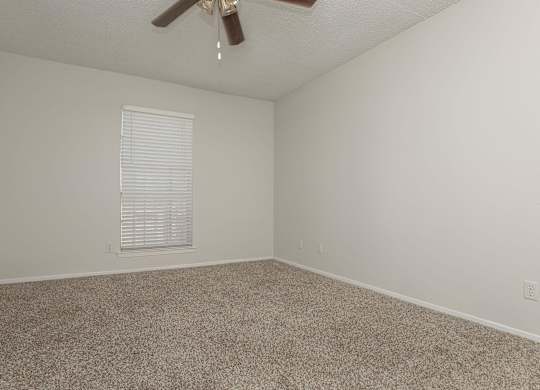 an empty room with carpet and a ceiling fan