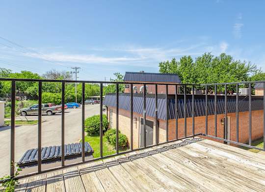 a balcony with a wooden deck and a brick building