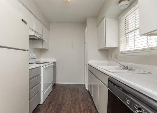a kitchen with white cabinets and white appliances and a wood floor