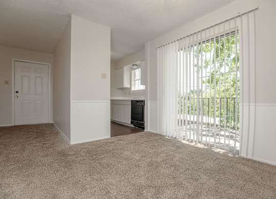 an empty living room with sliding glass doors to a balcony