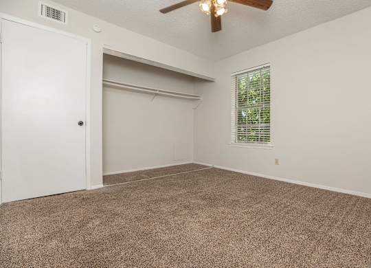 an empty living room with a ceiling fan and a window