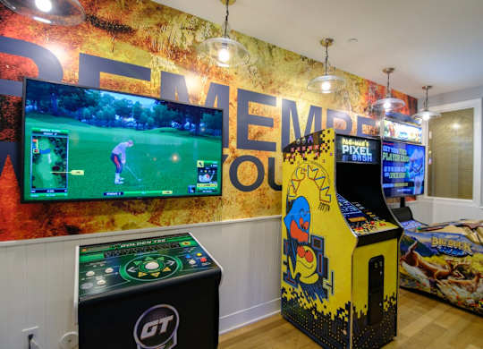 A room with a wall mural that says "Golf" and a row of arcade games.