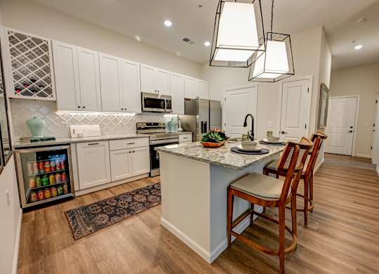 A kitchen with a white color scheme and wooden floors.