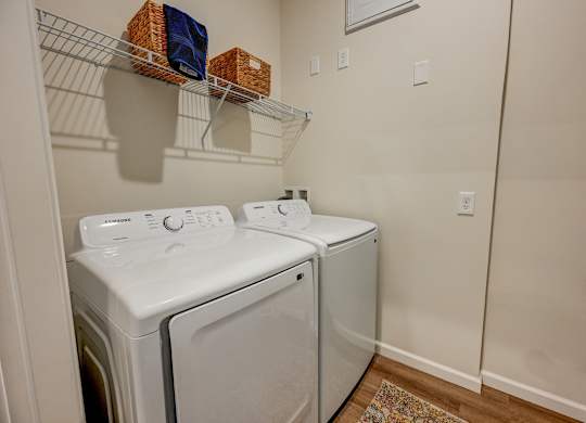 Two white front loading washing machines in a laundry room.