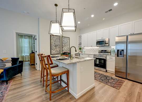 A kitchen with a white island and wooden chairs.