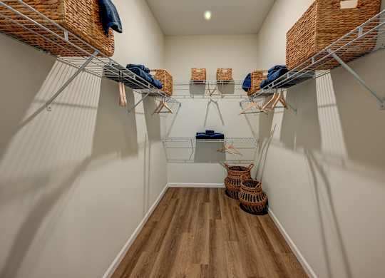 A walk-in closet with white walls and wooden floors.