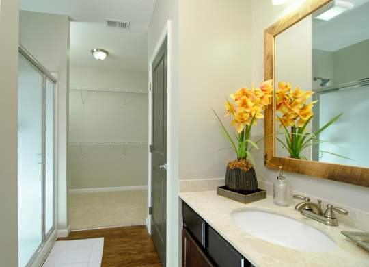 A bathroom with a sink, mirror, and a vase of flowers.