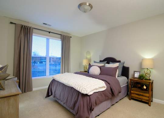 A bedroom with a bed, nightstand, and window.