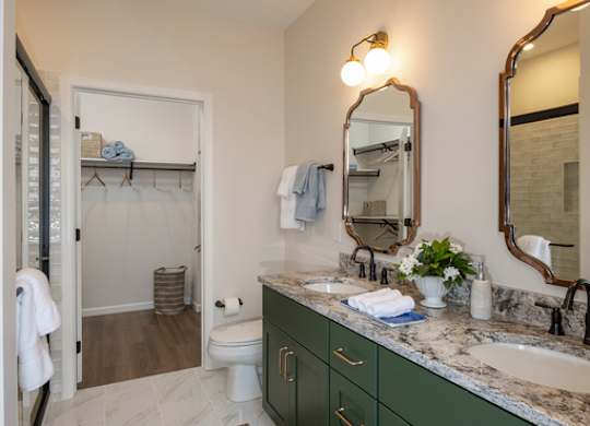A bathroom with green cabinets and a marble counter.