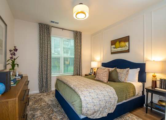 A bedroom with a bed, nightstand, and a vase on a dresser.