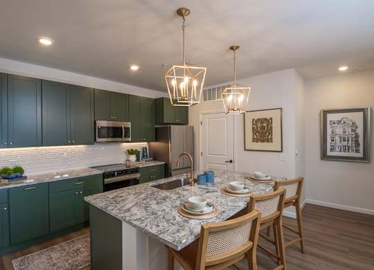 A kitchen with green cabinets and a marble countertop.