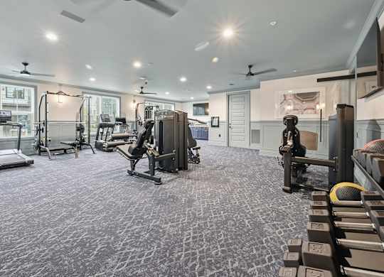 A spacious gym with a variety of equipment and a patterned carpet.