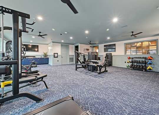A gym with a variety of equipment including treadmills, weights, and exercise machines.