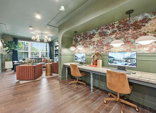 A room with a desk and chairs with a leafy wallpaper.