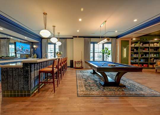 A room with a pool table and a bar area.