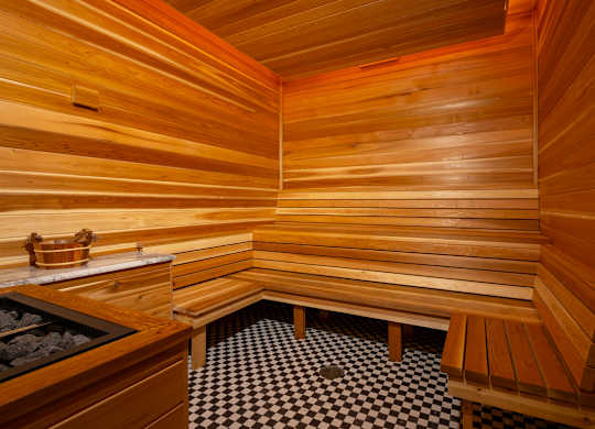 A wooden sauna with benches and a black and white checkered floor.