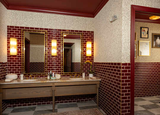 A bathroom with a checkered floor and a red wall.
