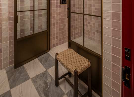A bathroom with a glass shower door and a bench.